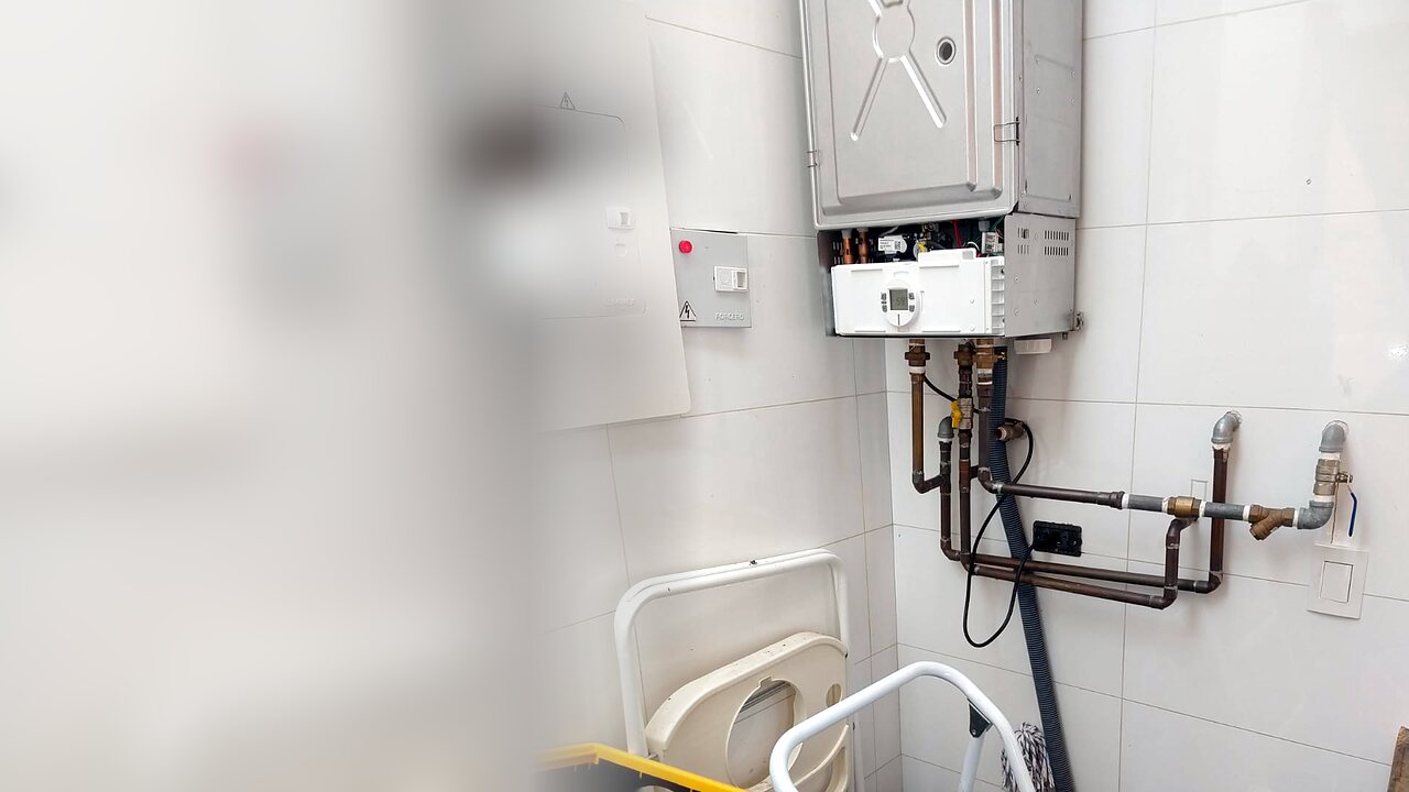 Caldera mural a gas abierta durante un mantenimiento, con sus tuberías de agua y gas